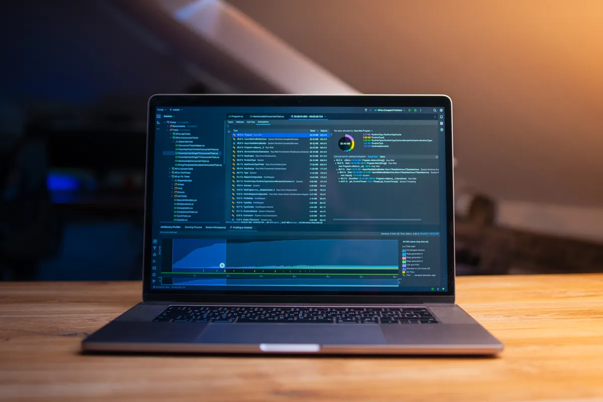 Laptop mit geöffnetem Code-Editor auf einem Holztisch